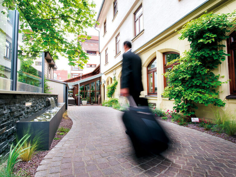 Business traveler arriving with suitcase at Ringhotel Gasthof Hasen in Herrenberg in Schönbuch Nature Park