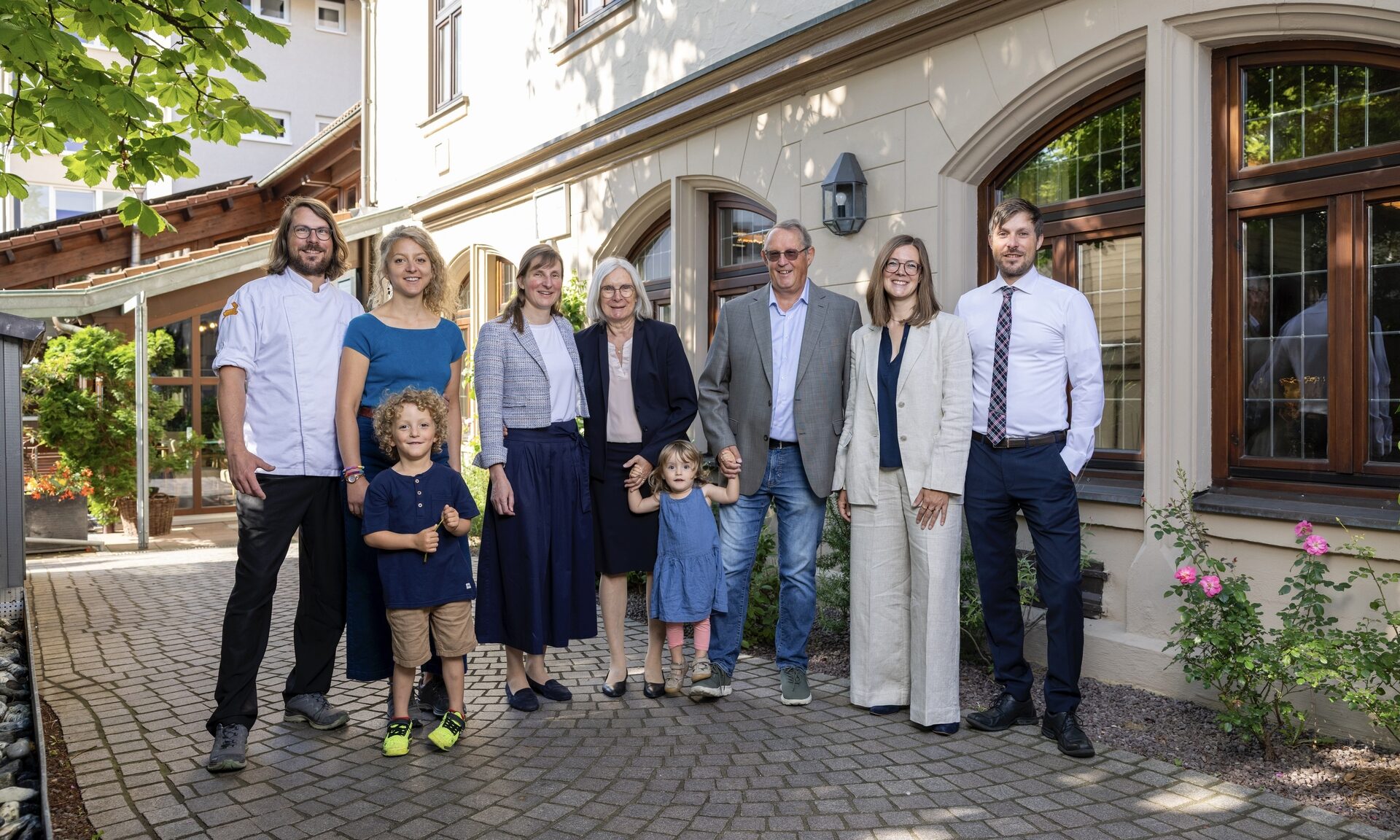 Mehrgenerationenfamilie spaziert gemeinsam vor dem Ringhotel Gasthof Hasen entlang eines gepflasterten Weges in freundlicher Atmosph&auml;re
